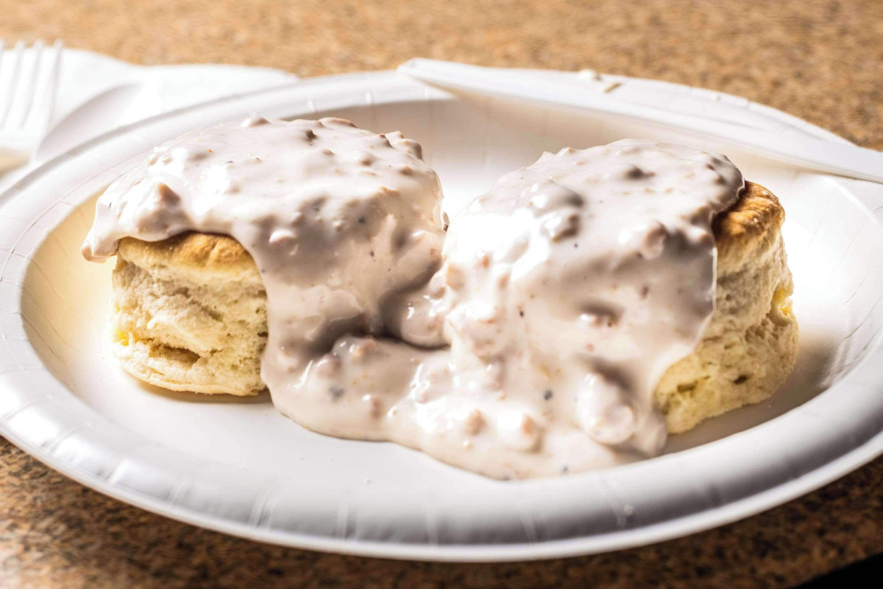 A plate with two biscuits covered in a creamy sauce.