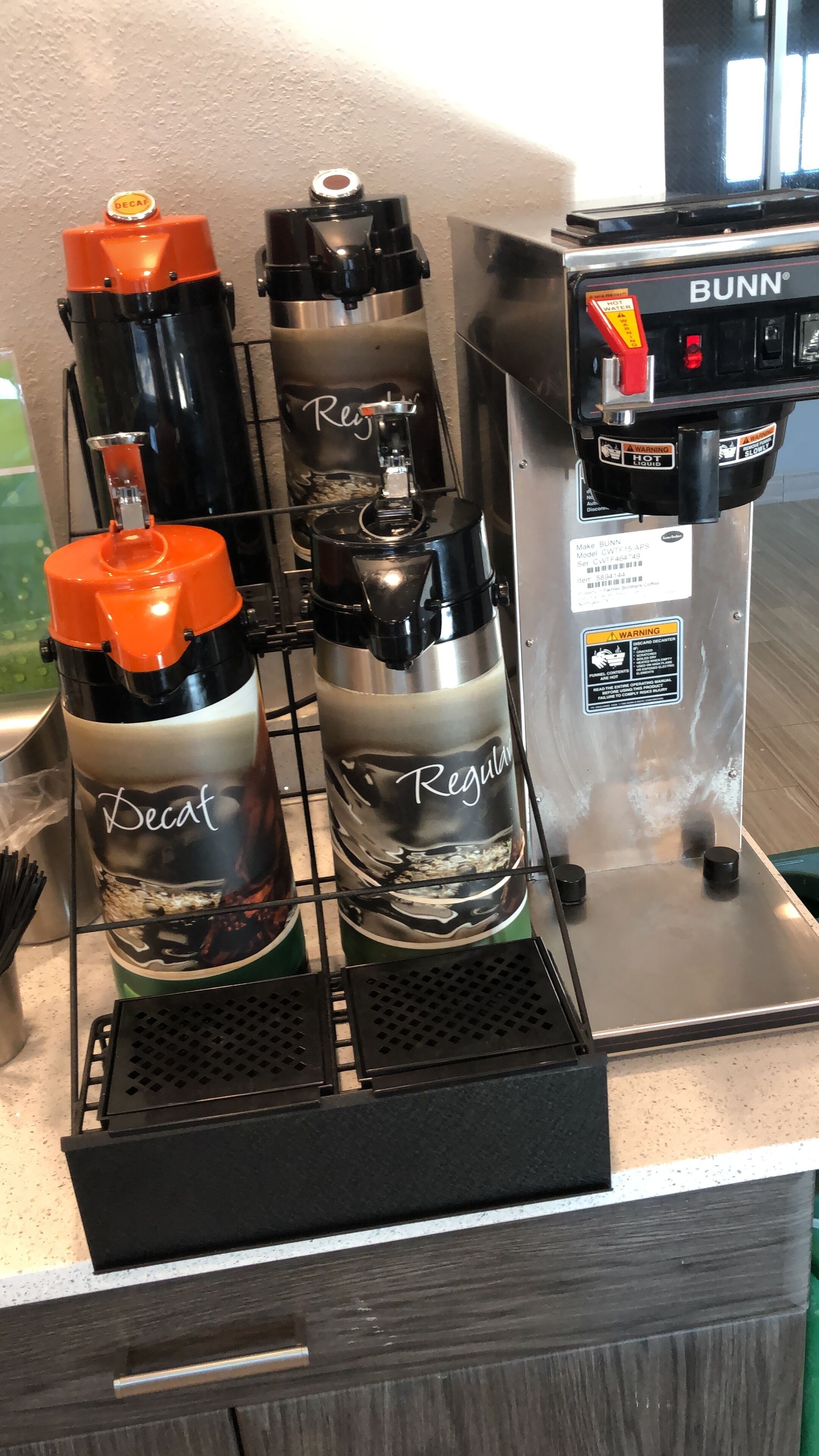 Una máquina de café con dos dispensadores de café descafeinado y dos de café regular, y una cafetera de la marca Bunn.