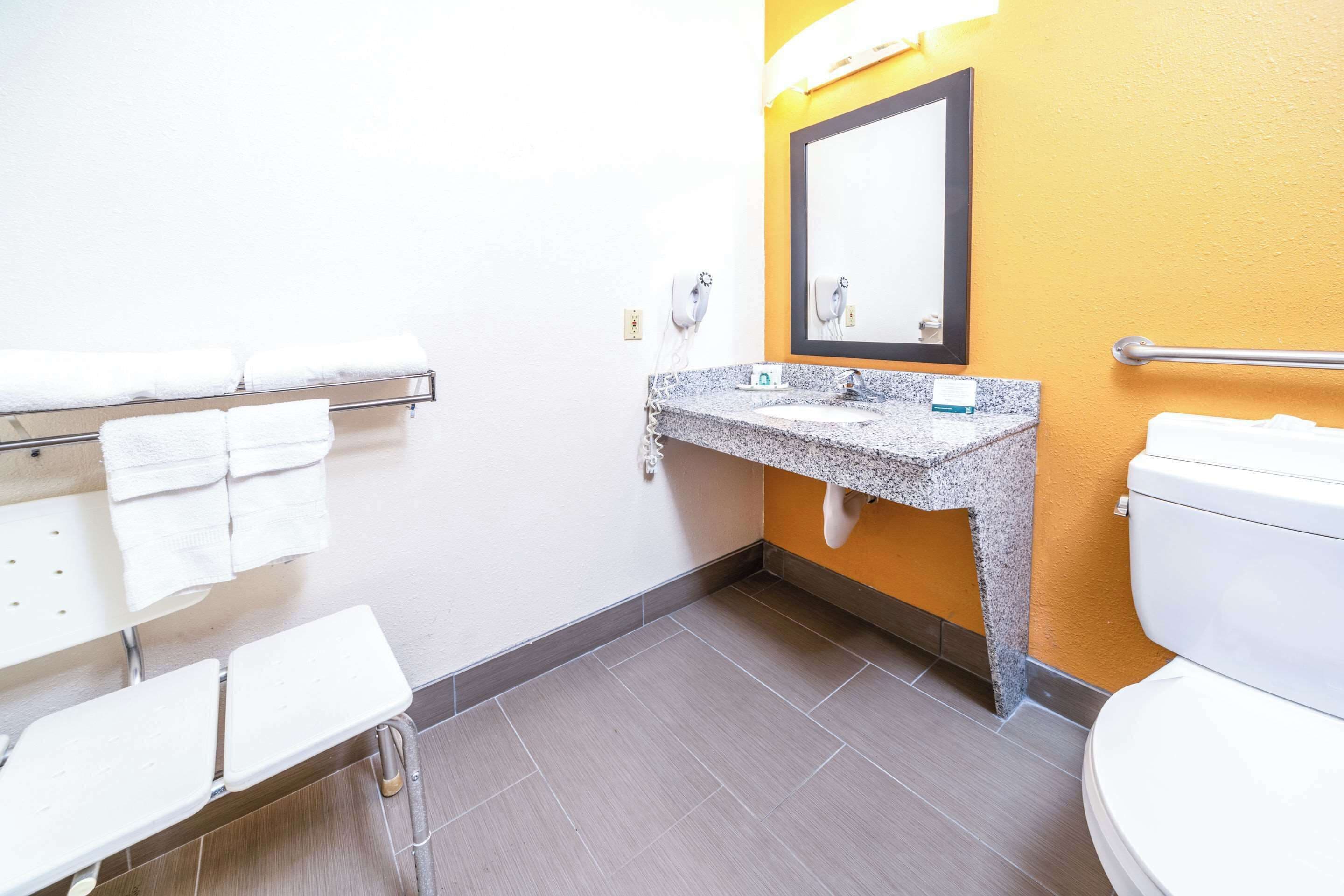 Une salle de bain avec un lavabo en granit, des toilettes blanches et un porte-serviettes avec plusieurs serviettes.