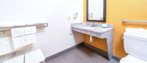 Une salle de bain avec un lavabo en granit, des toilettes blanches et un porte-serviettes avec plusieurs serviettes.