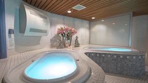 A spa area with two hot tubs, a wooden ceiling, and a tiled floor. - Fletcher Hotel - Restaurant De Klepperman (Hoevelaken)