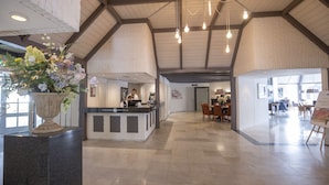 A hotel lobby with a reception desk, seating area, and a large vase of flowers. - Fletcher Hotel - Restaurant De Klepperman (Hoevelaken)