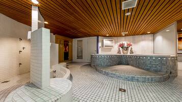 Area piscina interna moderna con soffitto in legno, pavimento piastrellato e vasca idromassaggio centrale.