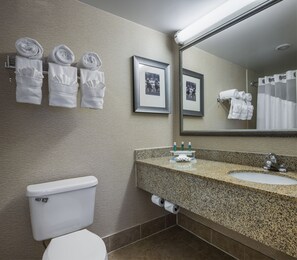 Un baño con inodoro, lavamanos y toallero con toallas.