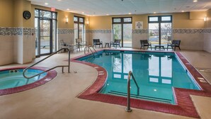 An indoor swimming pool with a red border, chairs, and a clock on the wall.