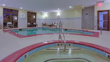 Una piscina interior con múltiples carriles, indicadores de profundidad y sillas de descanso.