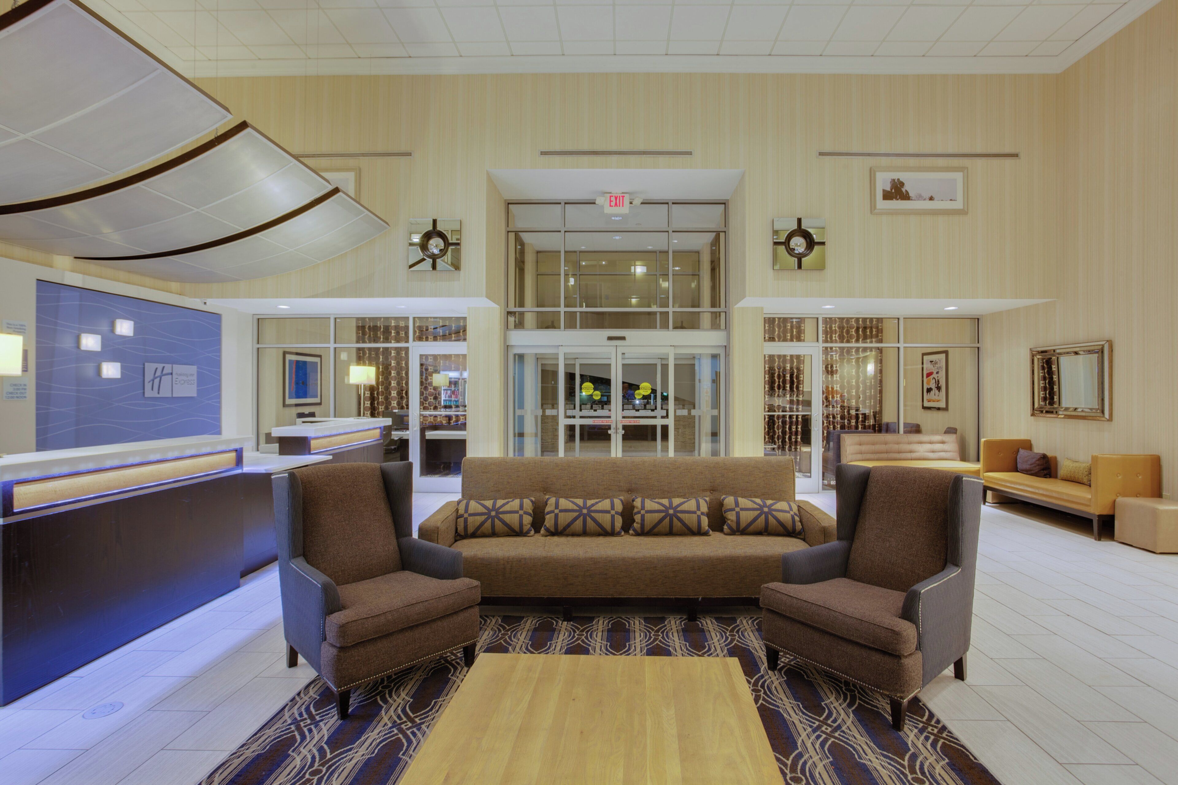 A lobby with a reception desk, a sofa, armchairs, and a patterned rug.