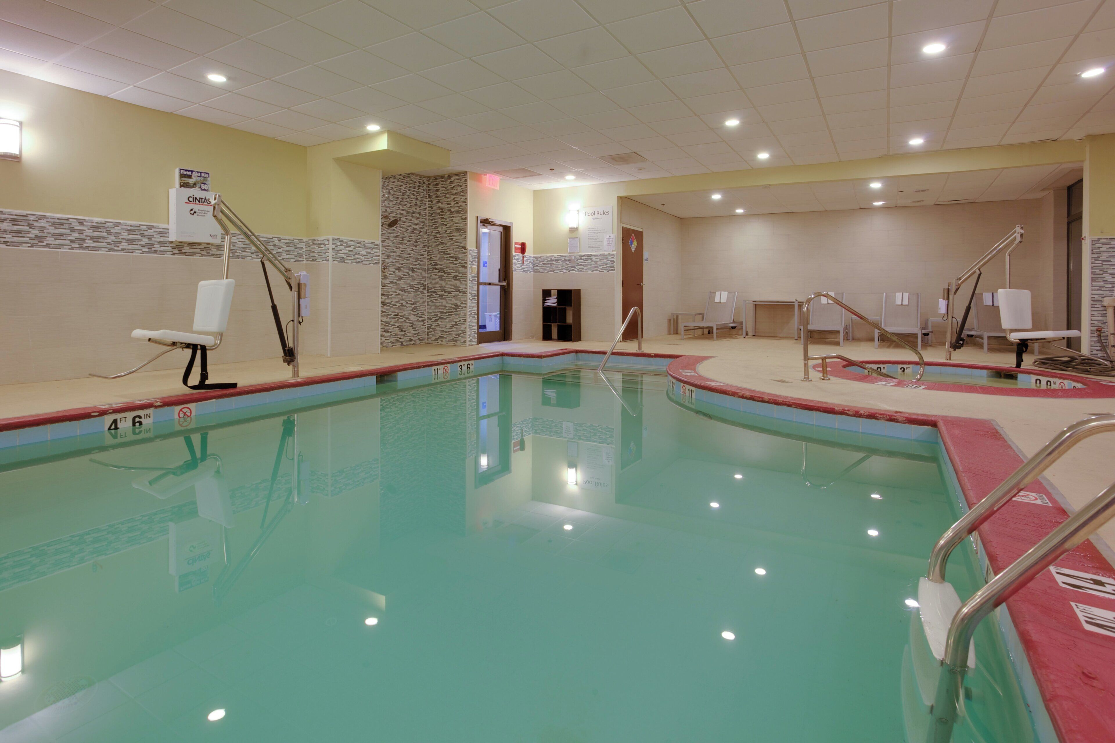 A swimming pool with a tiled edge, a changing room with a bench, and a door leading to an adjacent room.