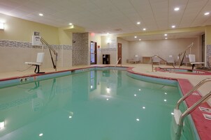 Una piscina con borde de azulejos, un vestuario con banco y una puerta que da a otra habitación.