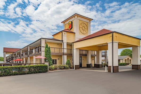 A hotel with a prominent clock tower, a covered entrance, and a pool area. - Super 8 by Wyndham Columbia (Columbia)