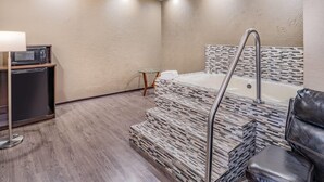Ein modernes Badezimmer mit Badewanne, Glastisch und Mikrowelle.