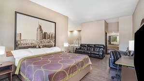 Ein Hotelzimmer mit einem großen Bett, einem Schreibtisch mit Stuhl, einer Ledersofa und einem Stadtbild an der Wand.