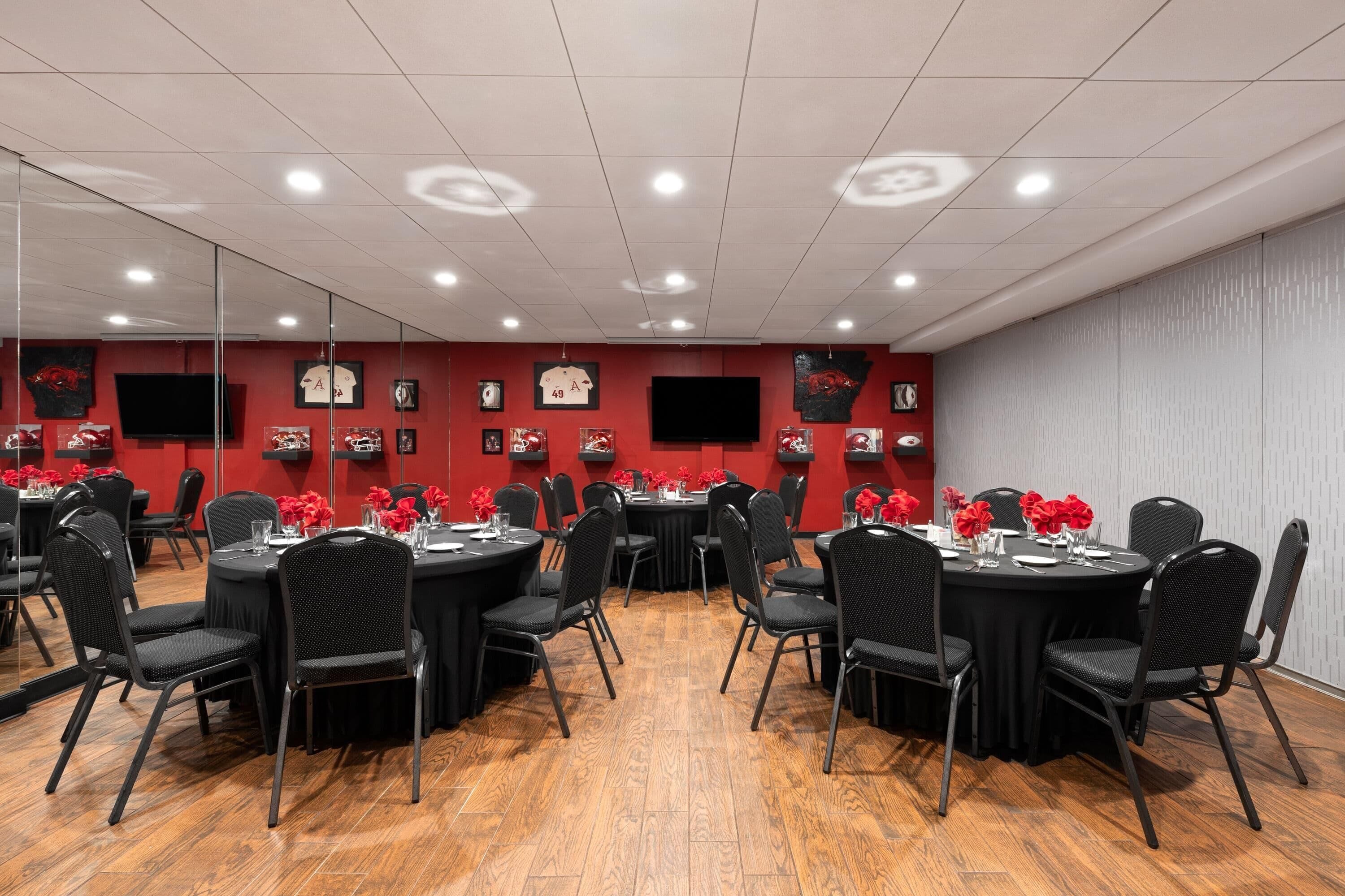 A conference room with round tables, black chairs, and red flowers.