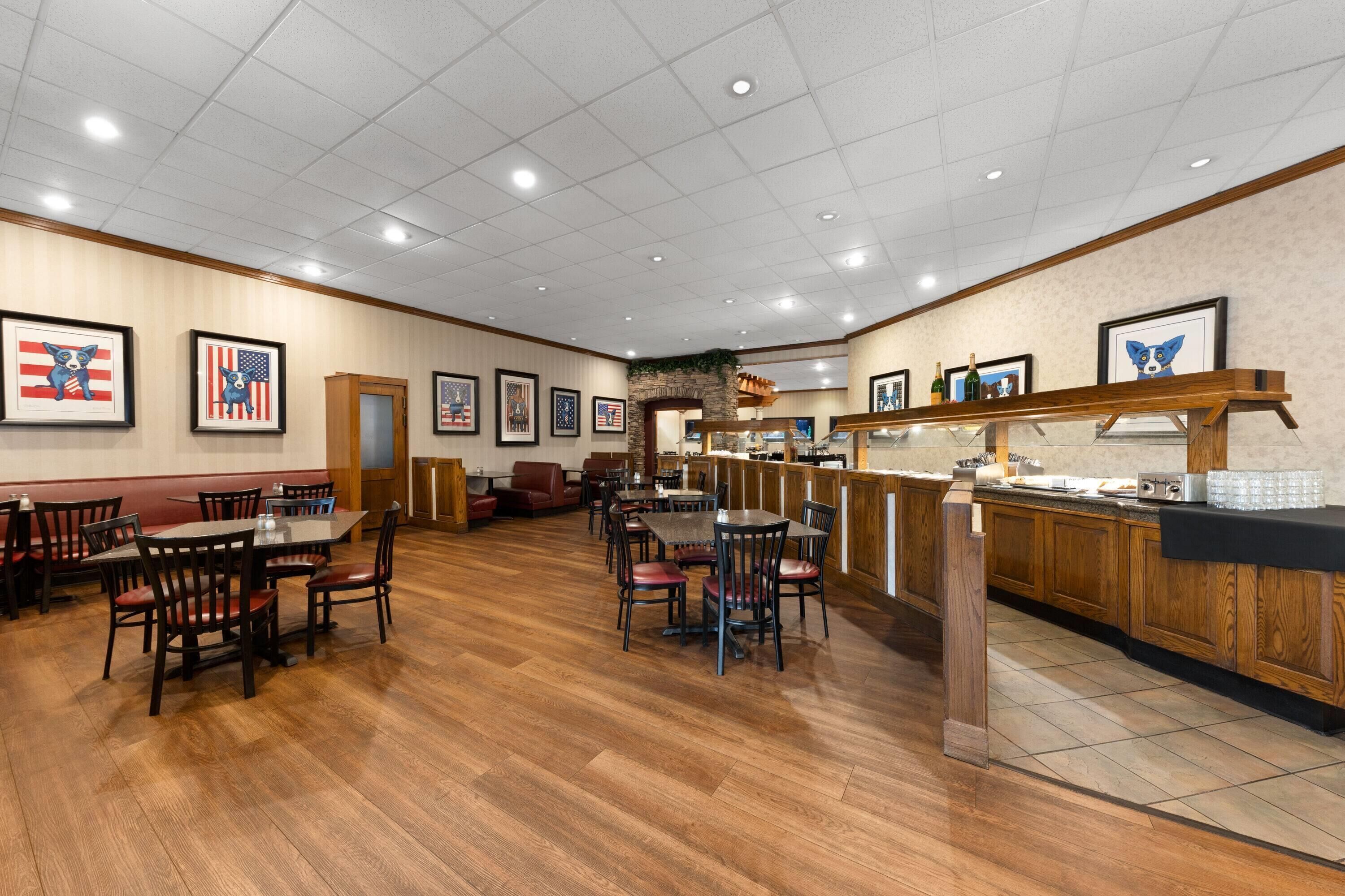 A restaurant with wooden flooring, tables, chairs, and a bar area with a counter.