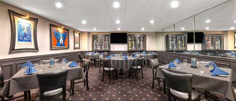 A conference room with round tables, chairs, and framed artwork on the walls.
