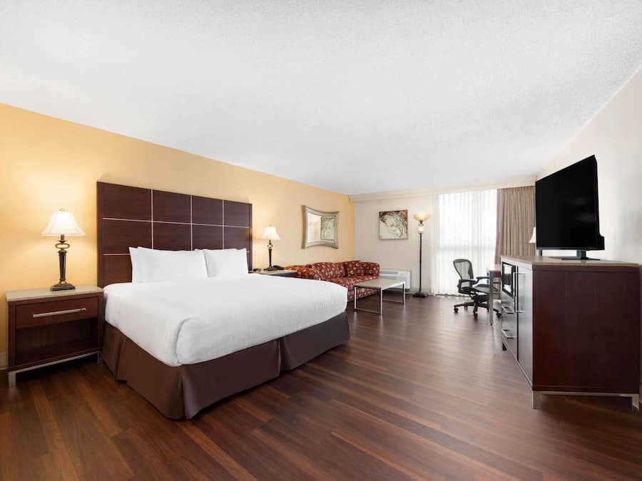 Ein Hotelzimmer mit einem großen Bett, einem Schreibtisch, einem Sessel, einem Fernseher und einer Couch.