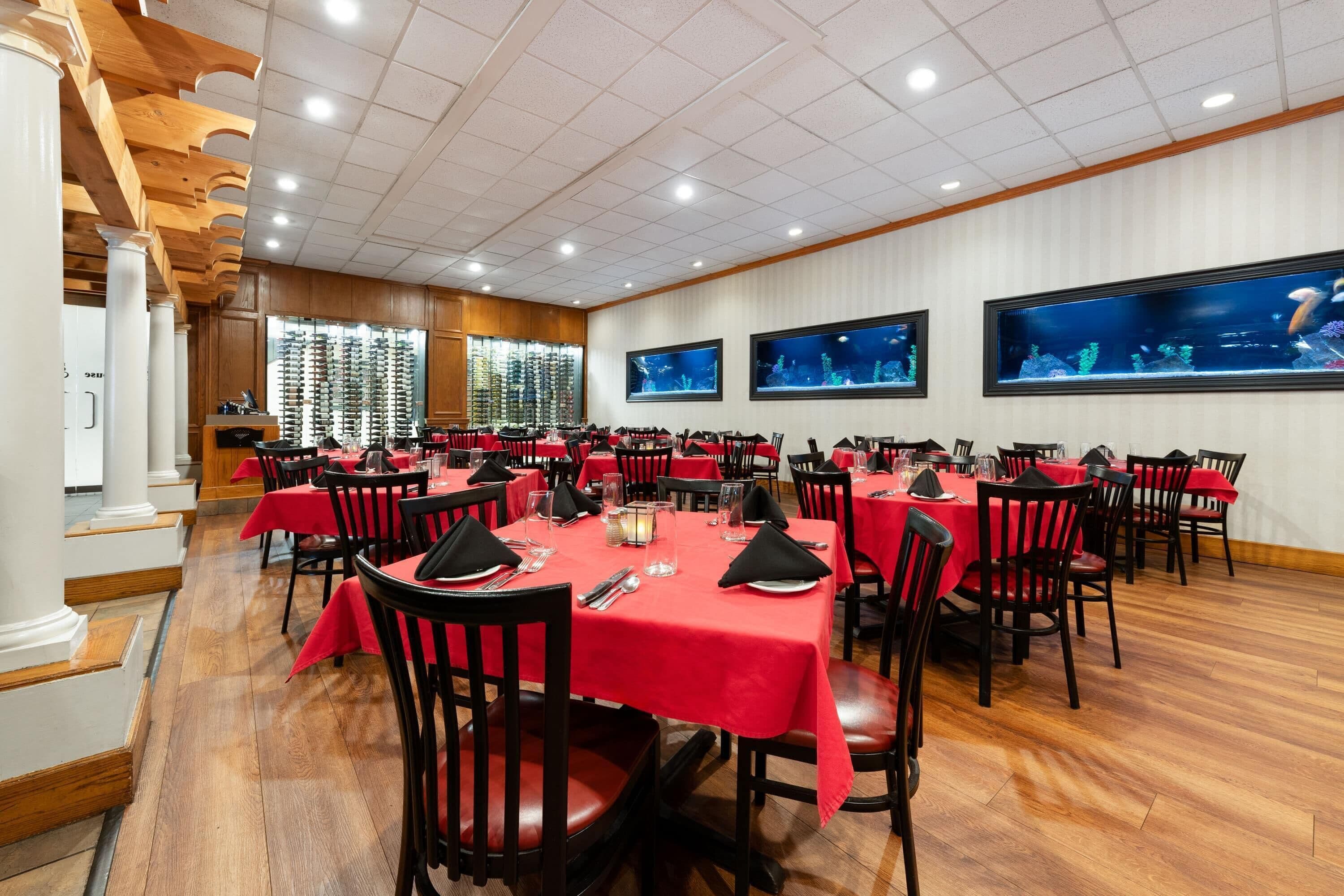 Une salle de conférence avec plusieurs tables, des nappes rouges et des chaises noires.