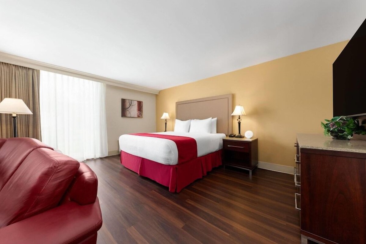 A hotel room with a bed, a desk, a chair, and a television.