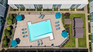 An aerial view of a hotel courtyard with a swimming pool, sun loungers, and a barbecue area. - Wyndham Riverfront Little Rock (North Little Rock)