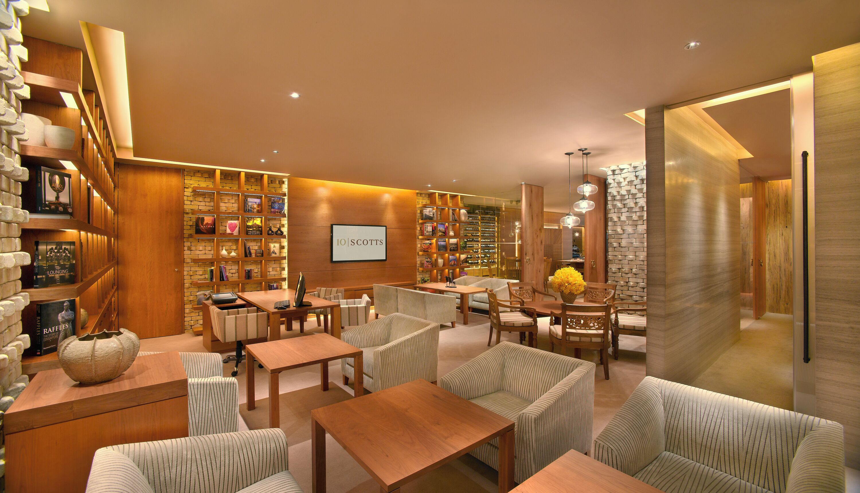 A modern lounge area with bookshelves, seating, and a central table.