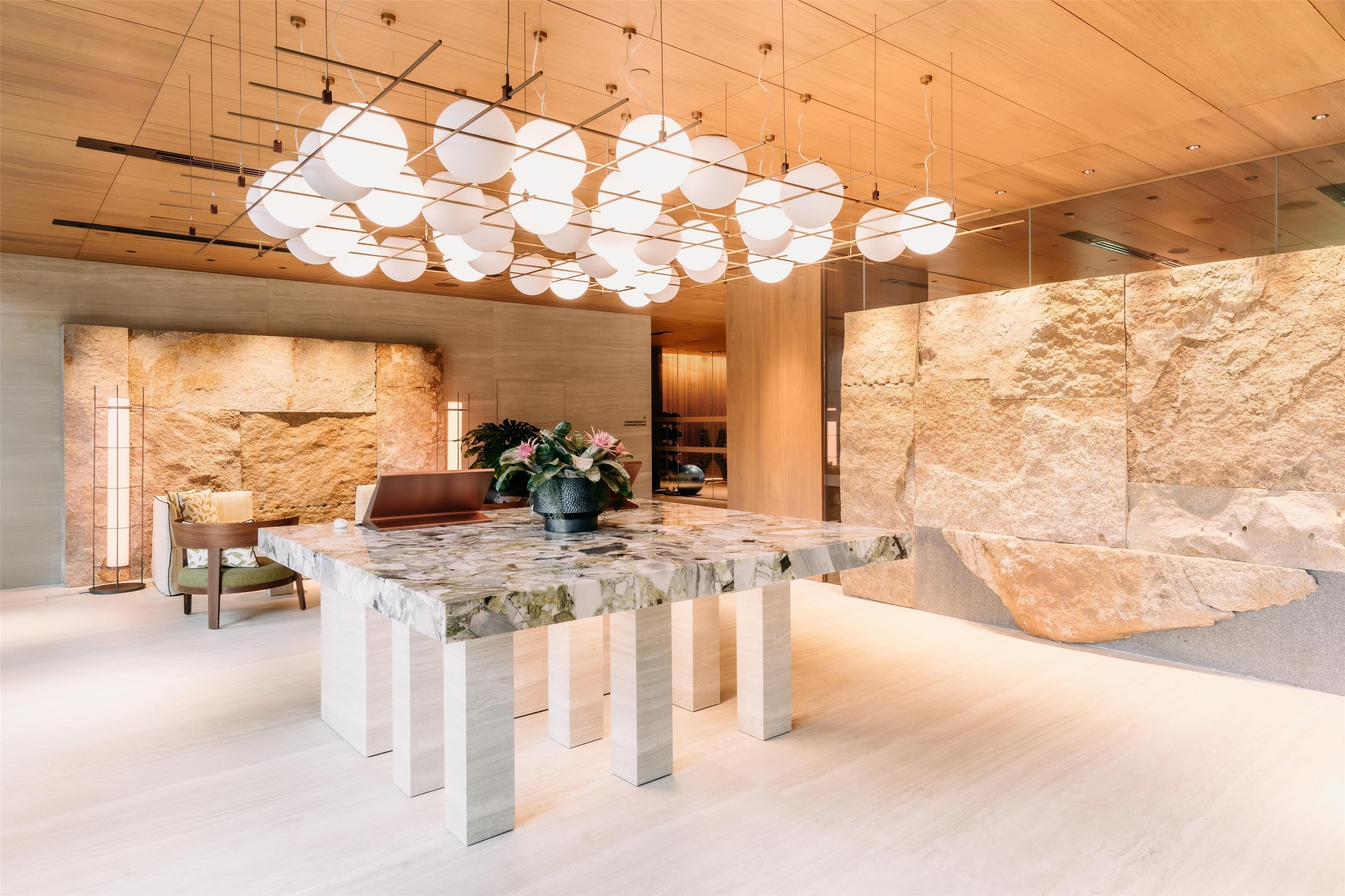 Un intérieur moderne avec une table en marbre, un mur en pierre et un luminaire au plafond au design unique.