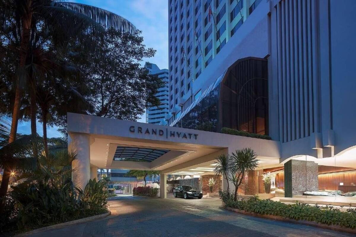 L’entrée d’un hôtel Grand Hyatt, avec une allée couverte, des palmiers et une façade moderne.