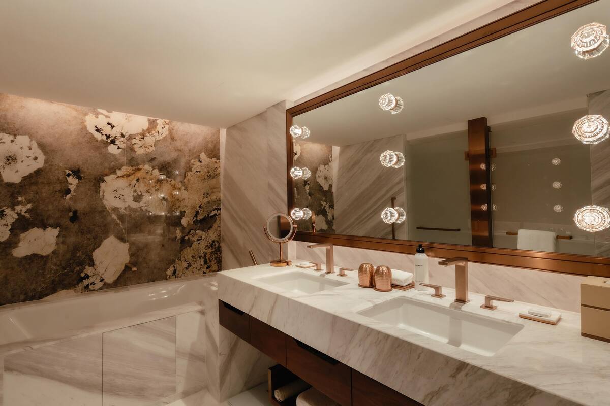 Une salle de bain avec un grand miroir, deux lavabos et une baignoire.