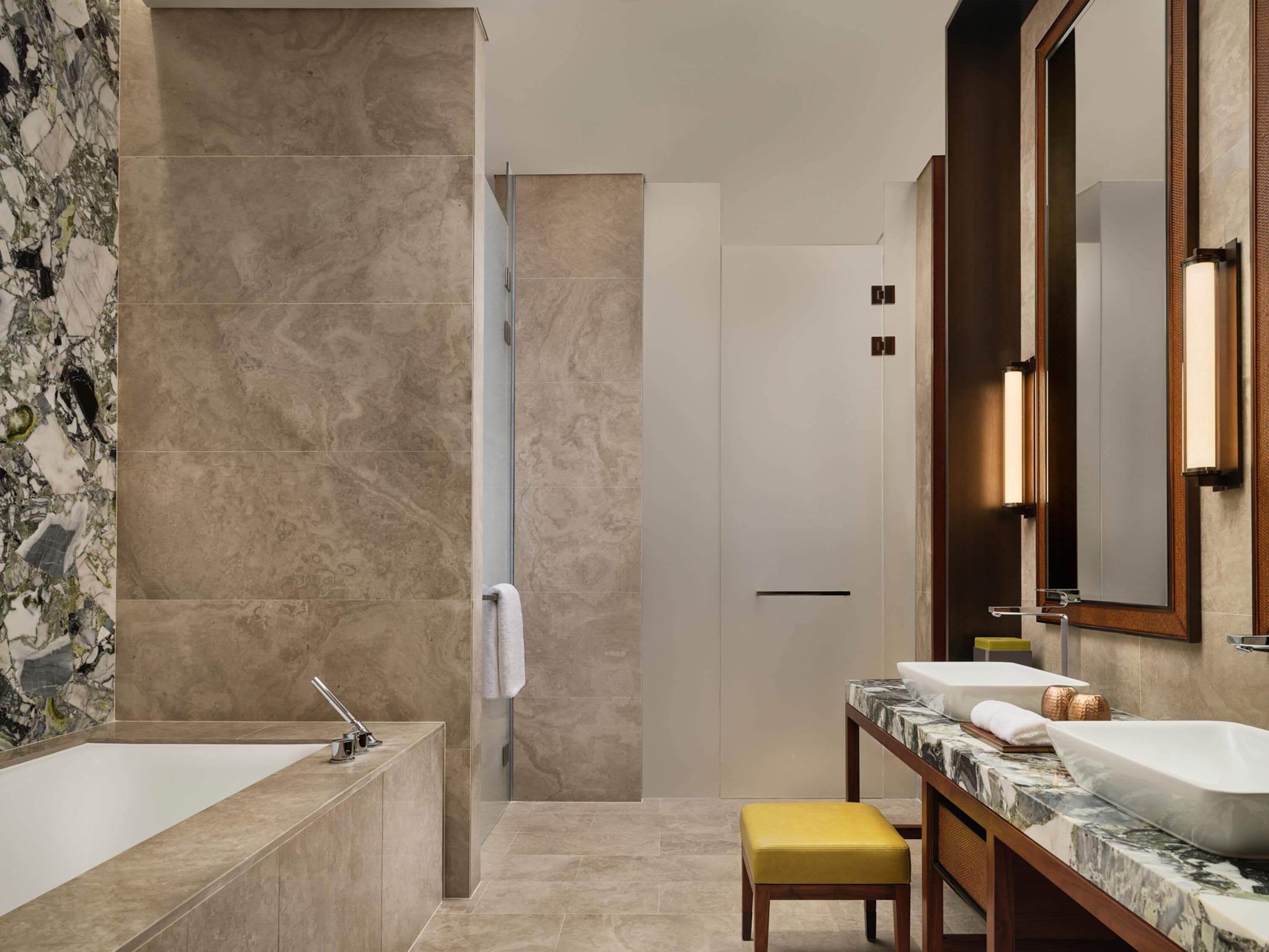 Een moderne badkamer met een bad, twee wastafels, een spiegel en een douche.