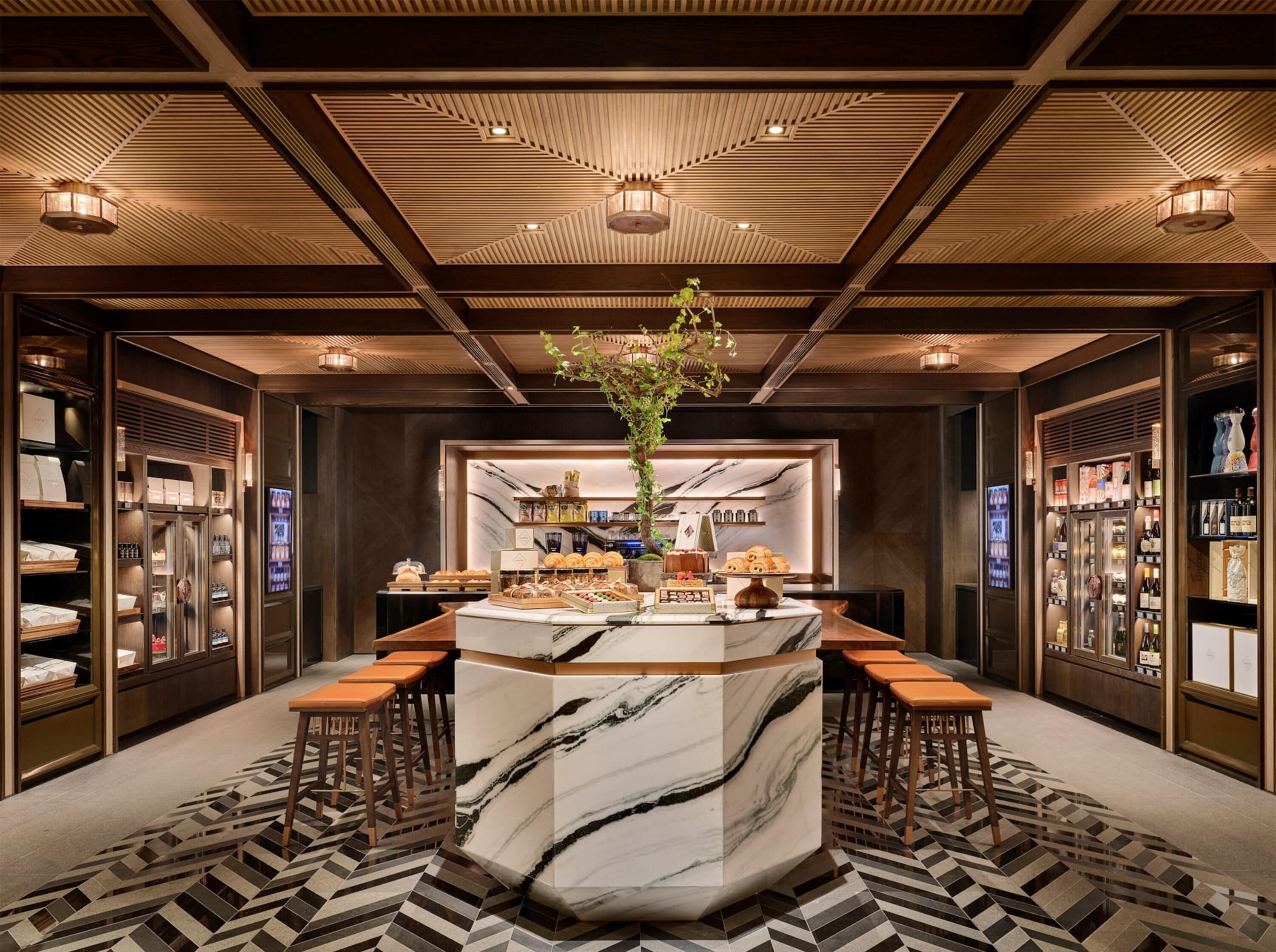 A modern hotel lobby with a marble reception desk, seating area, and display cases with amenities.