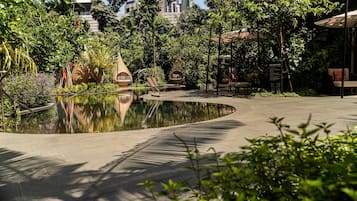 A serene outdoor area with a curved water feature, seating areas, and lush greenery.
