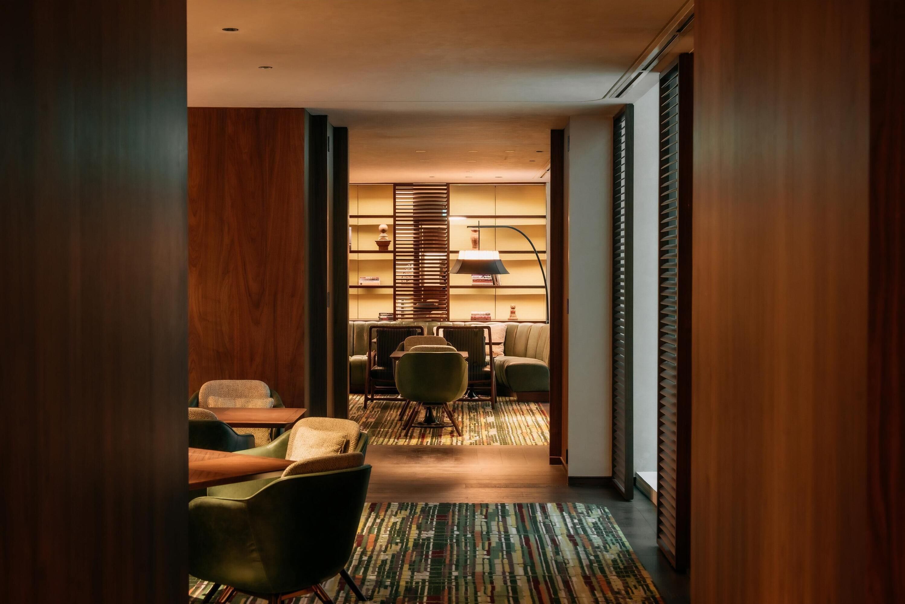 Un moderno vestíbulo de hotel con un mostrador de recepción de madera, zona de estar y alfombra estampada.