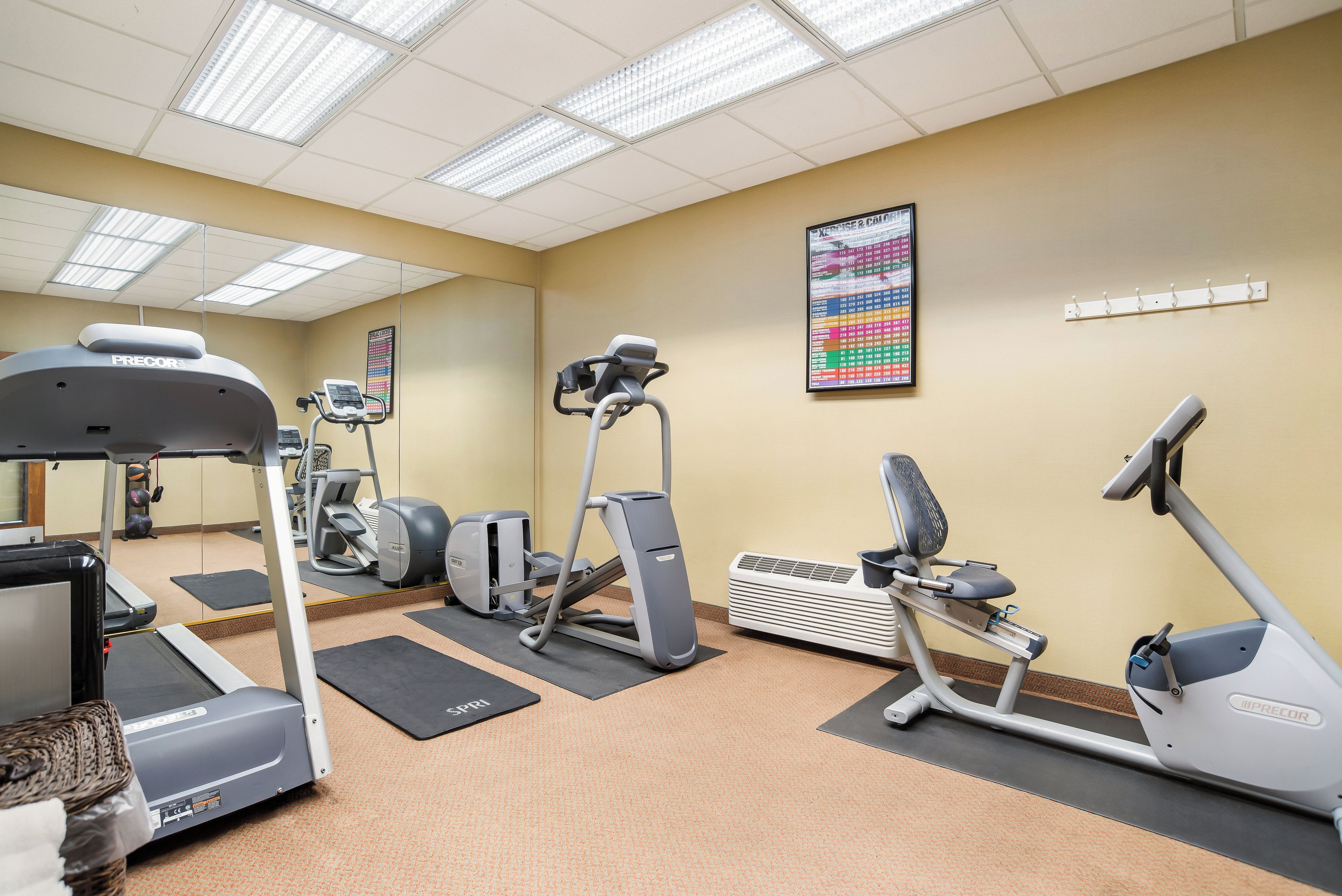 Un gimnasio con varias máquinas de ejercicio, incluyendo cintas de correr, una elíptica y una bicicleta estática.