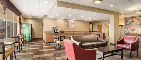A hotel lobby with a reception desk, seating area, and a coffee station.
