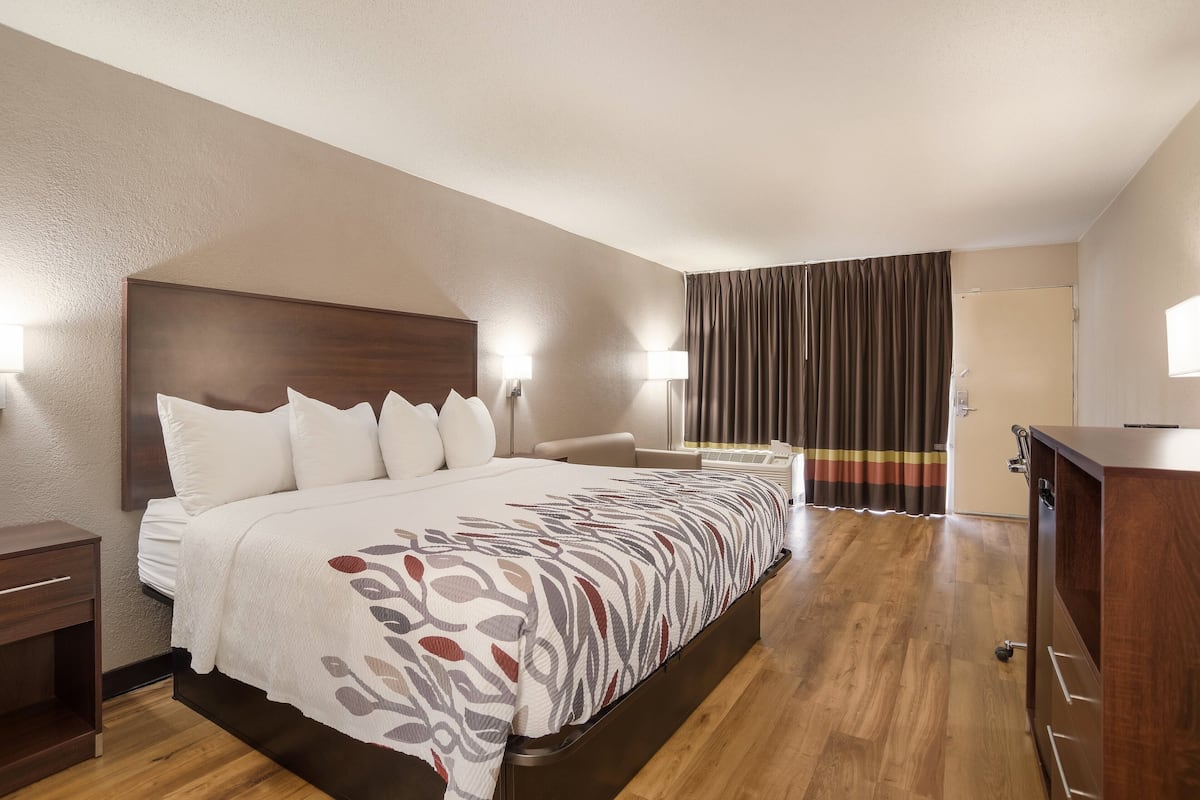 A hotel room with a large bed, bedside lamps, a desk, and a wardrobe.