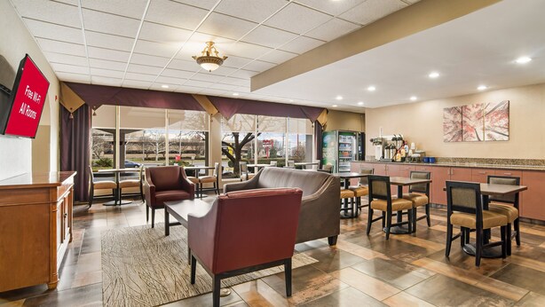 A hotel lobby with a seating area, a reception desk, and a kitchen visible through the glass doors. - Red Roof Inn Baltimore South - Glen Burnie (Glen Burnie)