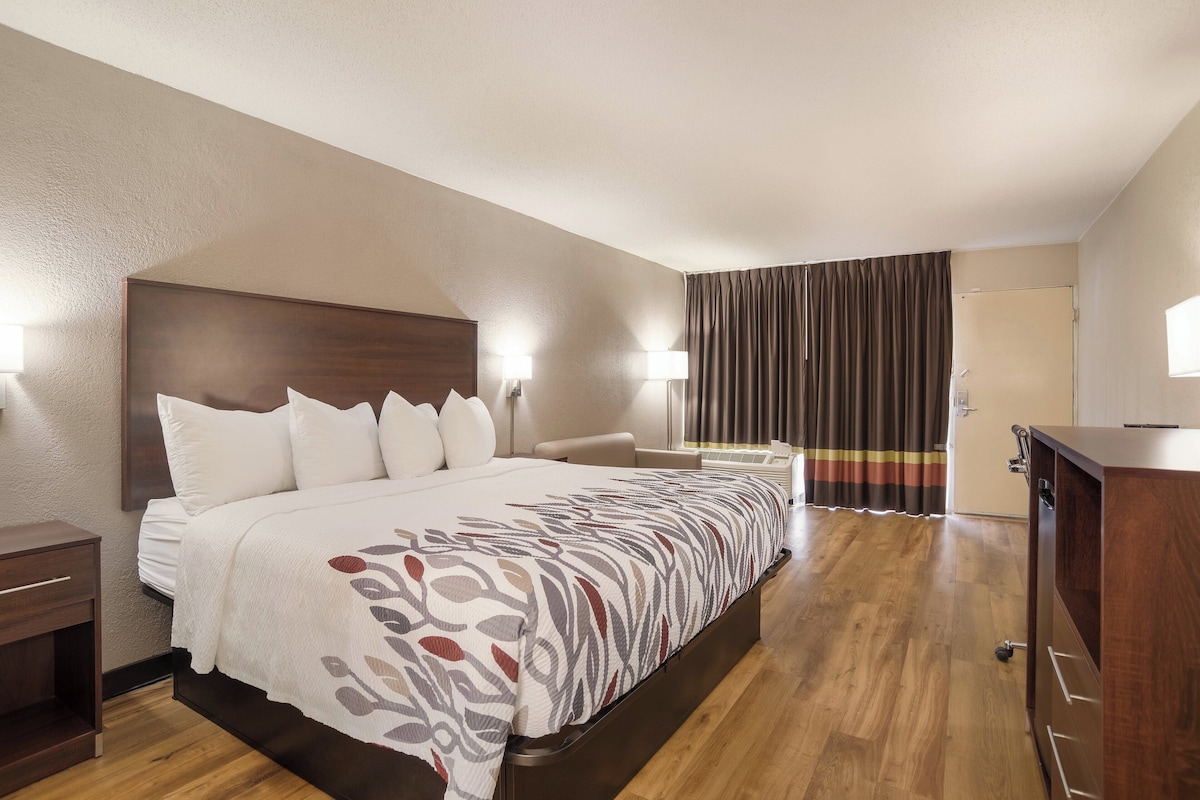 Una habitación de hotel con una cama grande, lámparas de noche, un escritorio y un armario.