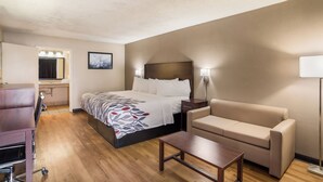 Une chambre d’hôtel comprenant un lit, un canapé, un bureau et une salle de bain avec un miroir et un lavabo.