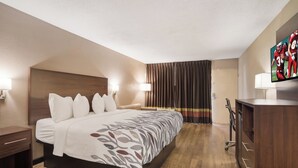 Une chambre d’hôtel comprenant un lit, des lampes de chevet, une télévision, un bureau et une armoire.