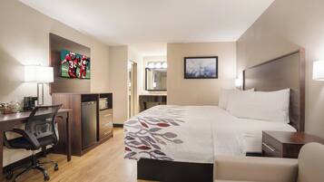 A hotel room with a bed, desk, chair, and a television.