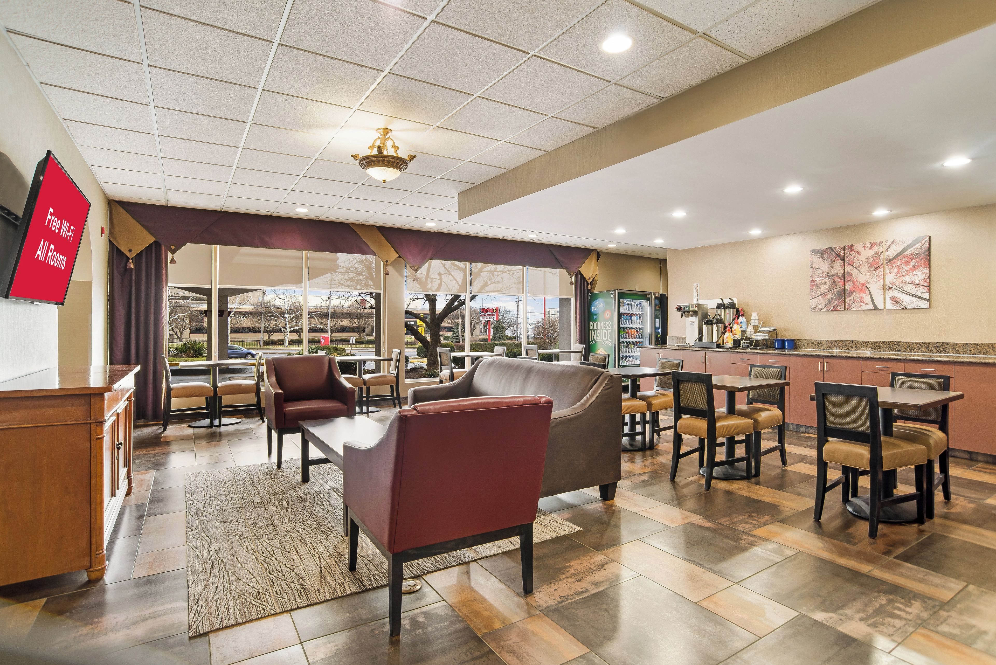 A hotel lobby with seating areas, a kitchenette, and a large window offering a view.
