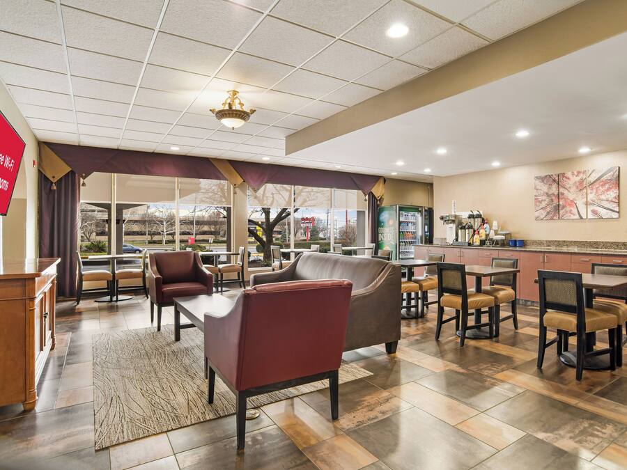 A hotel lobby with seating areas, a kitchenette, and a large window offering a view.
