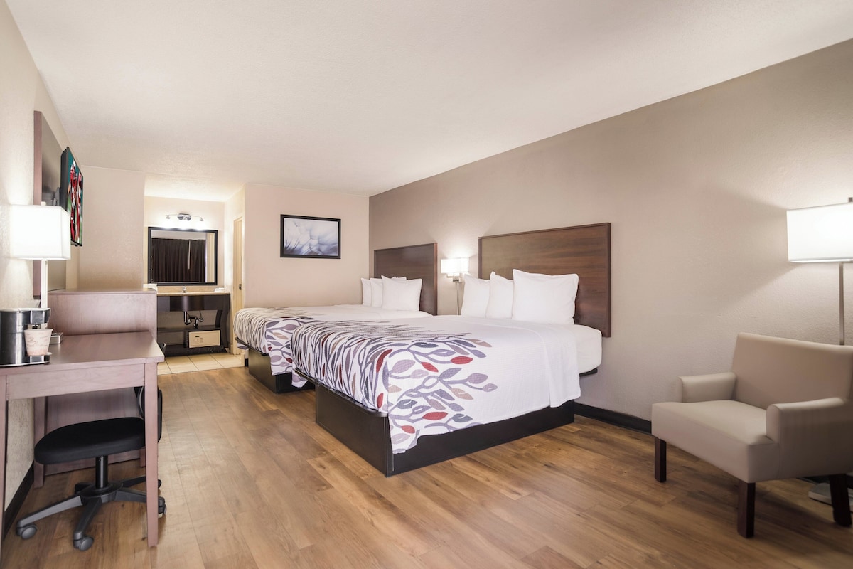 Habitación de hotel con cama, escritorio, silla y baño con espejo.