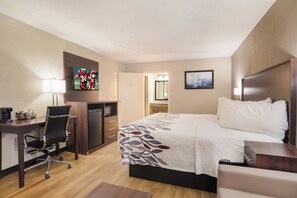 Hotelkamer met een bed, bureau, stoel, televisie en een badkamer zichtbaar door een geopende deur.