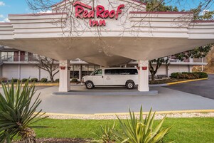 Un hotel Red Roof Inn con una camioneta blanca estacionada bajo el toldo del edificio.