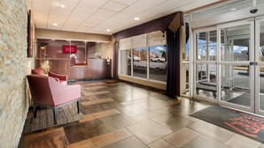 A hotel lobby with a reception desk, a seating area, and a view of the parking lot through large glass doors. - Red Roof Inn Baltimore South - Glen Burnie (Glen Burnie)