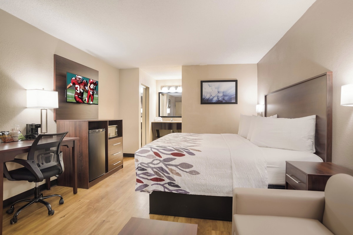 Una habitación de hotel con cama, escritorio, silla y televisor.