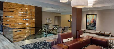 A modern lobby with a wooden wall, seating area, and a staircase.
