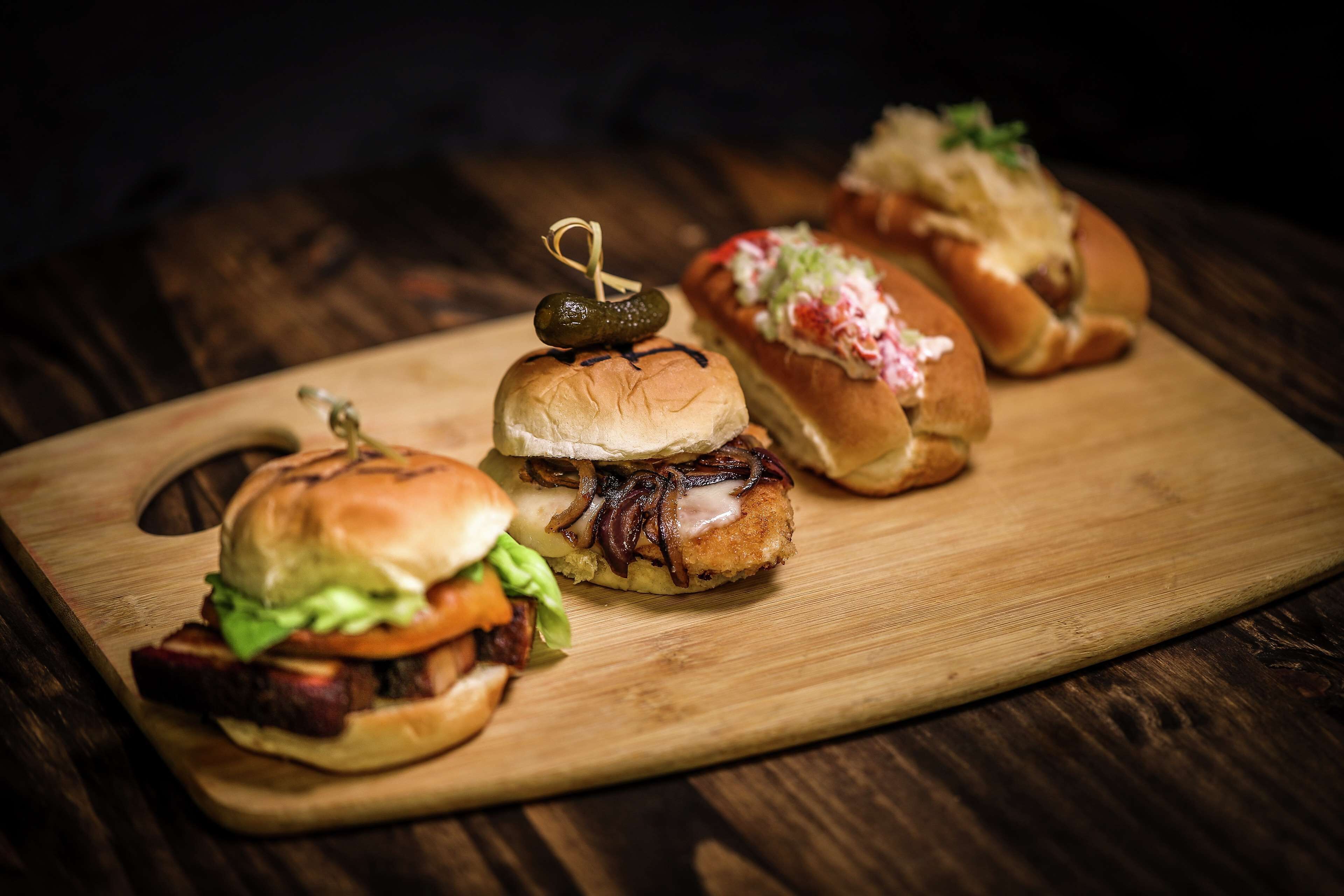 A wooden cutting board with three sandwiches.