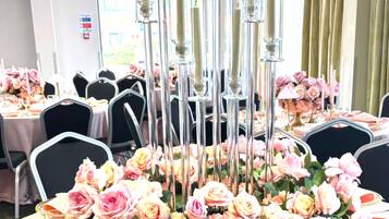 Une table de banquet décorée de roses roses, de porte-bougies en verre transparent et d’ornements dorés.