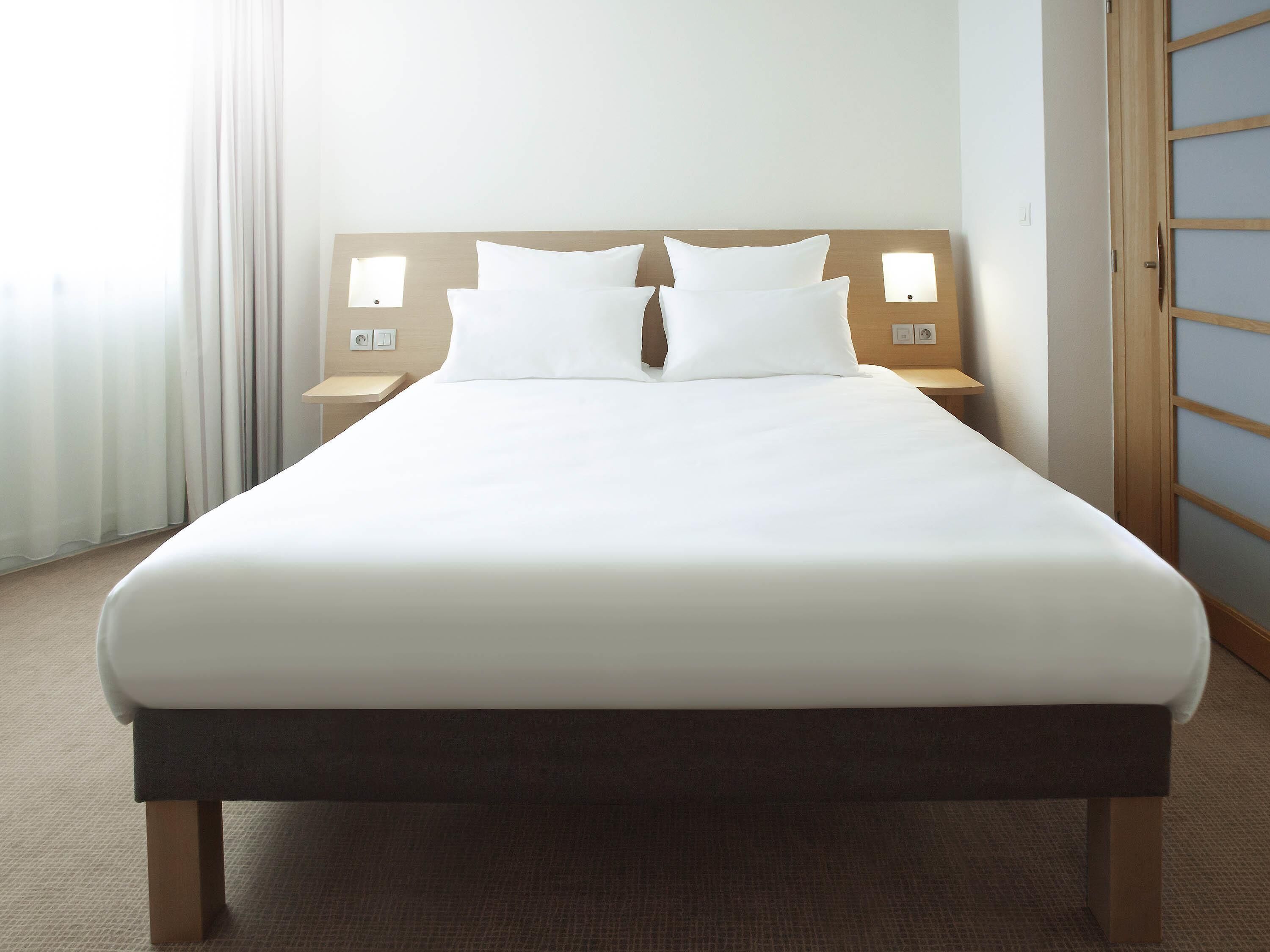 Une chambre d’hôtel avec un grand lit, deux tables de chevet et une tête de lit en bois.